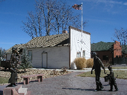 Miners Museum building in Frederick, with statues of a family in the foreground and the American fla…