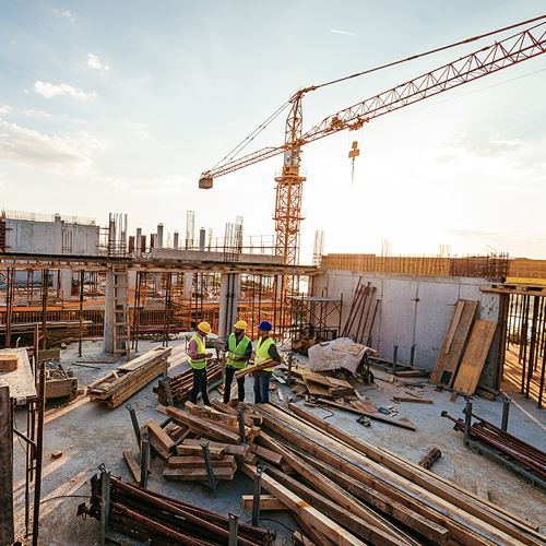 [Image Description: Three construction workers on the roof of a building under construction]