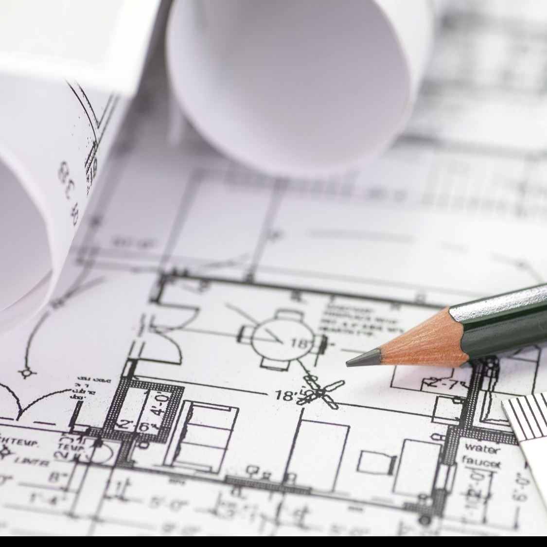 Close-up of architectural blueprints with a pencil resting on the plans, along with rolled-up bluepr