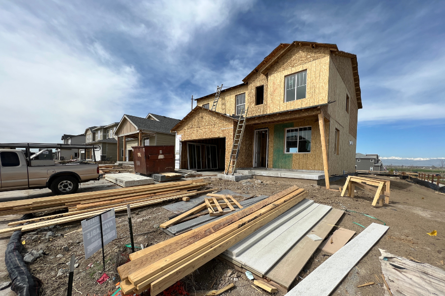 Construction site showing a two-story house in progress, with lumber and building materials